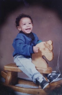 a young boy sitting on a wooden rocking horse
