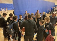 a group of people gathered around a basketball court