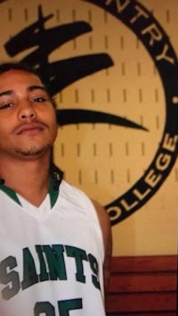 a man in a basketball uniform standing in front of a sign
