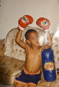 a young boy with boxing gloves on a couch