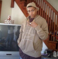 a young man in a tan hoodie standing in front of a tv