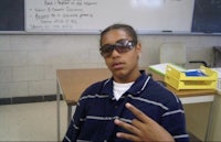 a young man in sunglasses sitting in a classroom