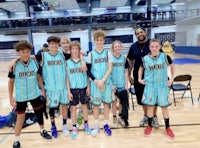 a group of young people posing for a picture on a basketball court