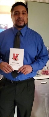 a man in a blue shirt and tie holding a book