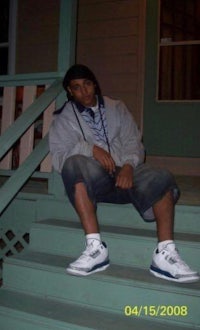 a young man sitting on the steps of a house