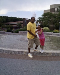 a man and a girl standing next to a fountain
