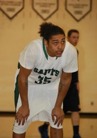 a man in a green and white uniform standing on a basketball court