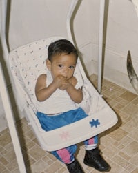 a baby sitting in a swing with a cow in the background